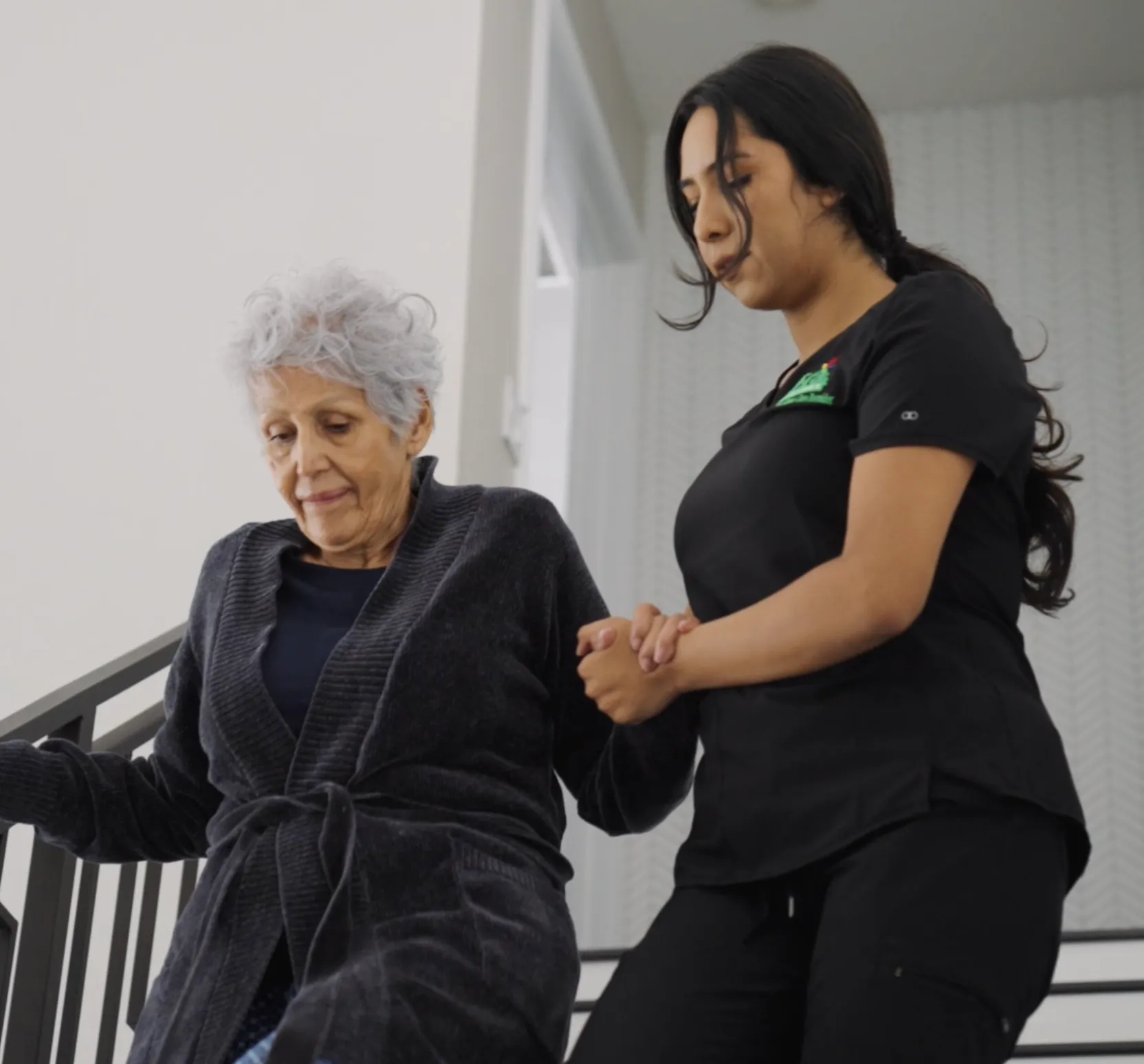 Era Life Care caregiver helping an older woman walk down the stairs at home