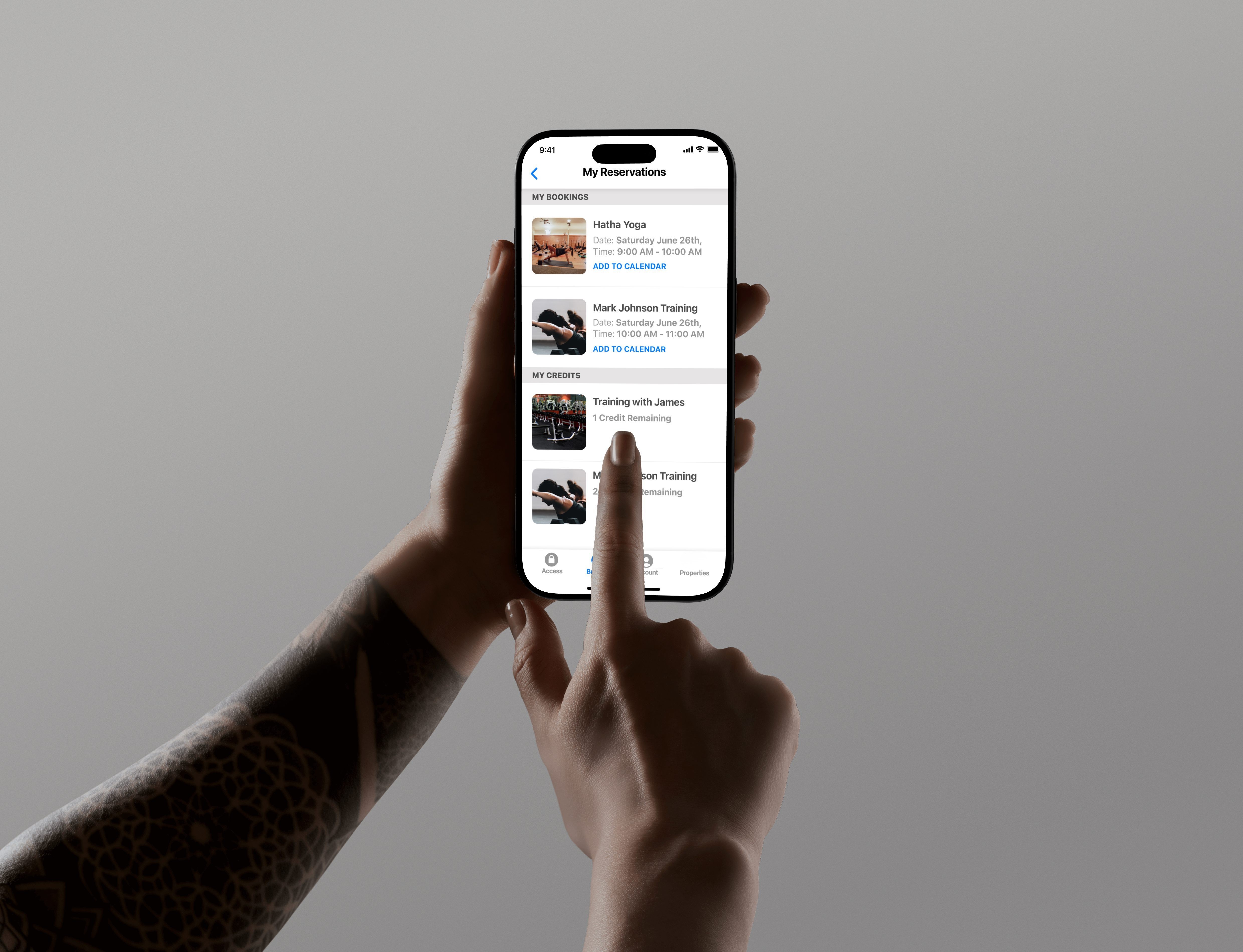 Hand holding smartphone displaying My Reservations app with yoga and training bookings