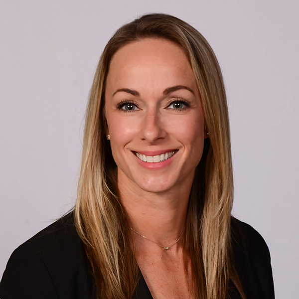 Portrait of smiling woman with brown hair wearing black shirt, neutral background