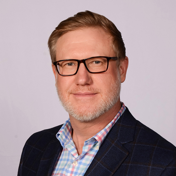 Man with glasses wearing navy plaid jacket and checkered shirt portrait