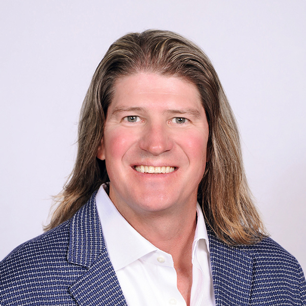 Portrait of man with long brown hair wearing navy blazer and white shirt