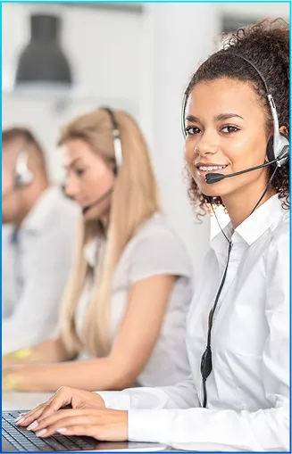 A group of customer service representatives wearing headsets, focused on their tasks at a modern office desk.