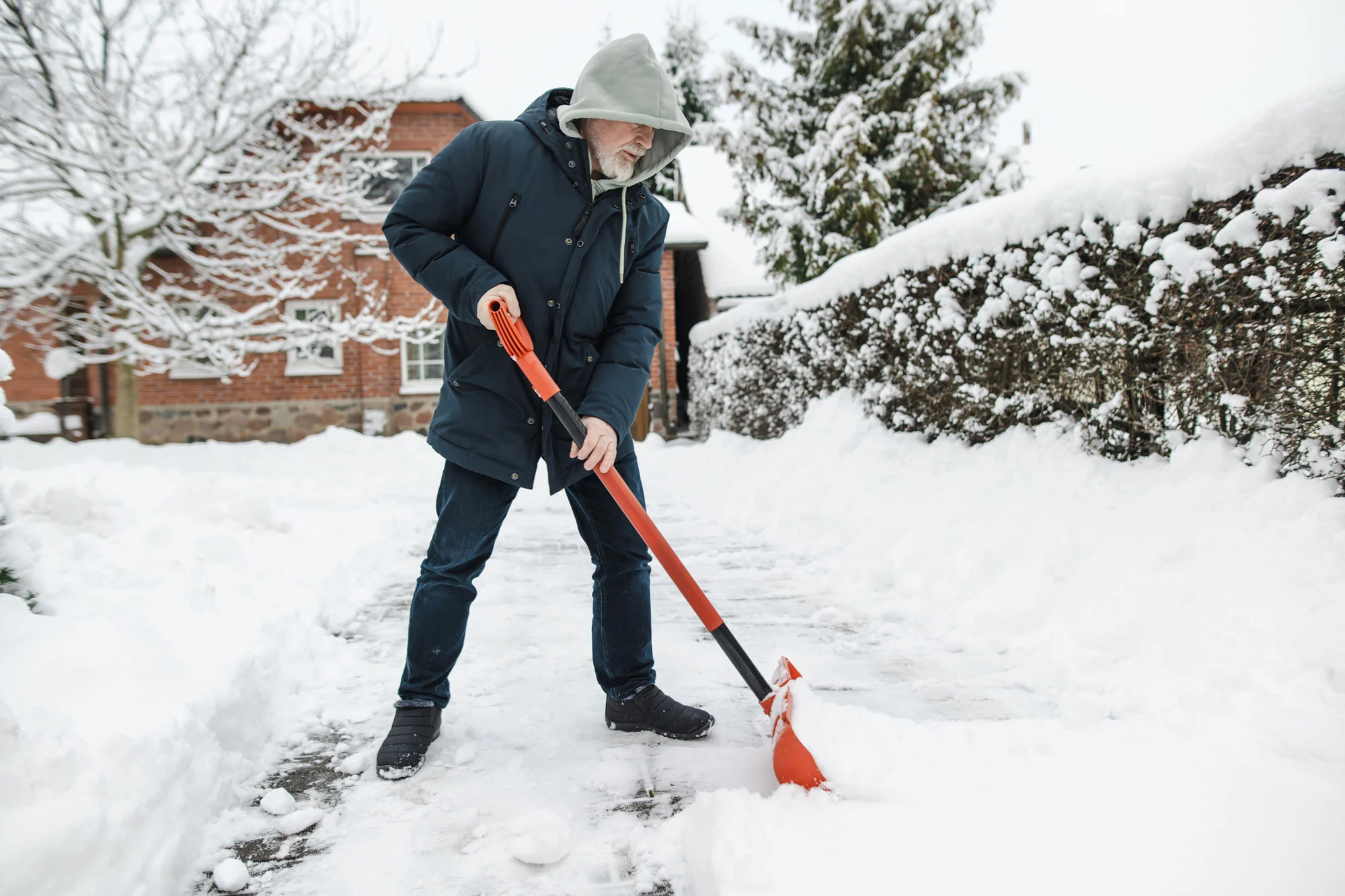 Man shovelling snow from a residential driveway after a winter snowfall.