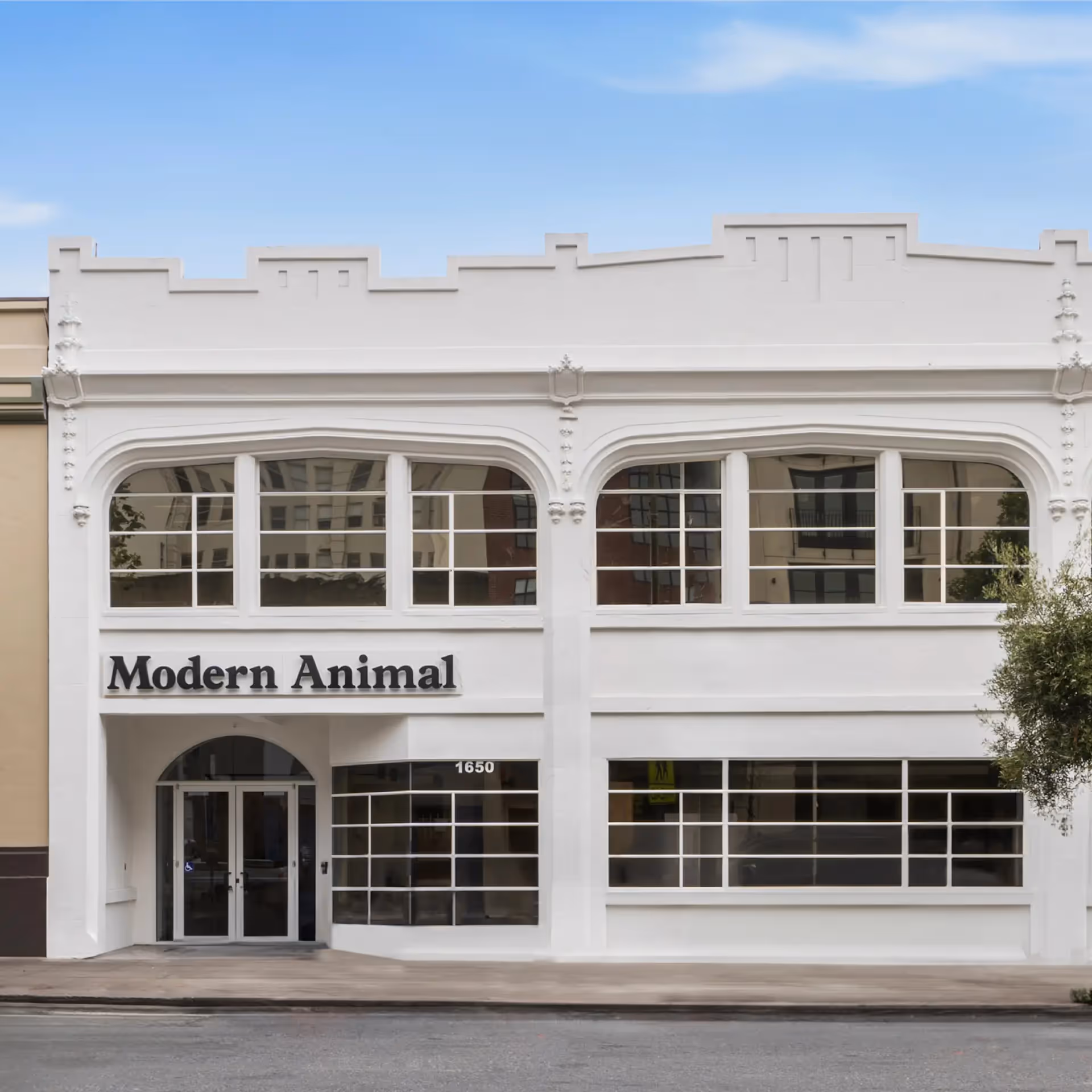 White two-story building with arched windows and a sign that says Modern Animal above the entrance at 1650.