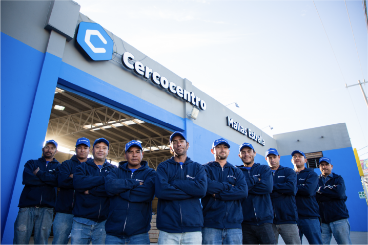 Team of nine men in blue jackets and caps standing with arms crossed in front of a Cercocentro building.