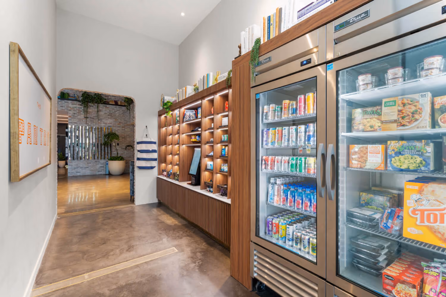 refrigerated section in market lobby with pizzas, drinks and other frozen foods with self checkout
