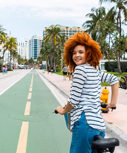 woman riding bike with blue jeans and white shirt in miami