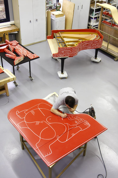 Artisan applying custom decoration to a bespoke grand piano case