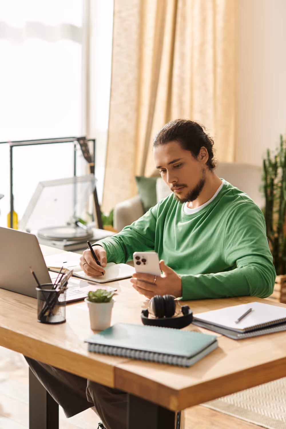 Two young women sitting on wooden steps, one holding a laptop and phone while both smile and laugh together.