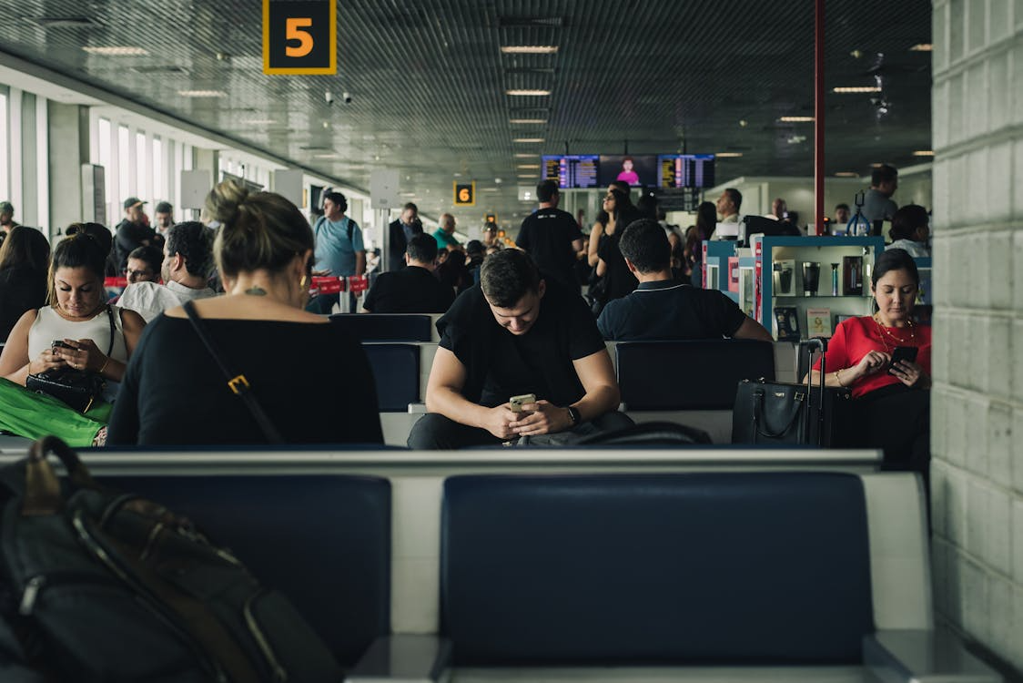  Crowded airport terminal with travelers using laptops and phones on public Wi-Fi