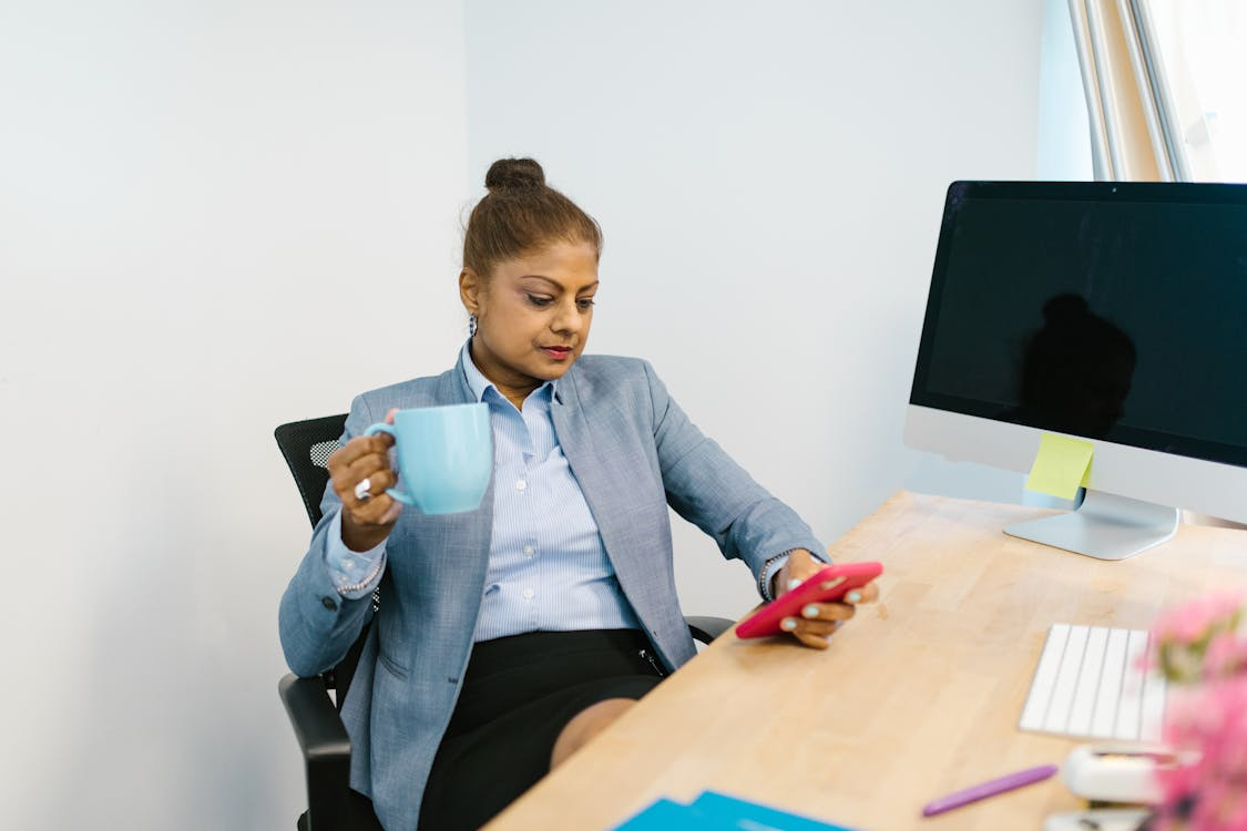 woman holding a blue ceramic mug while texting