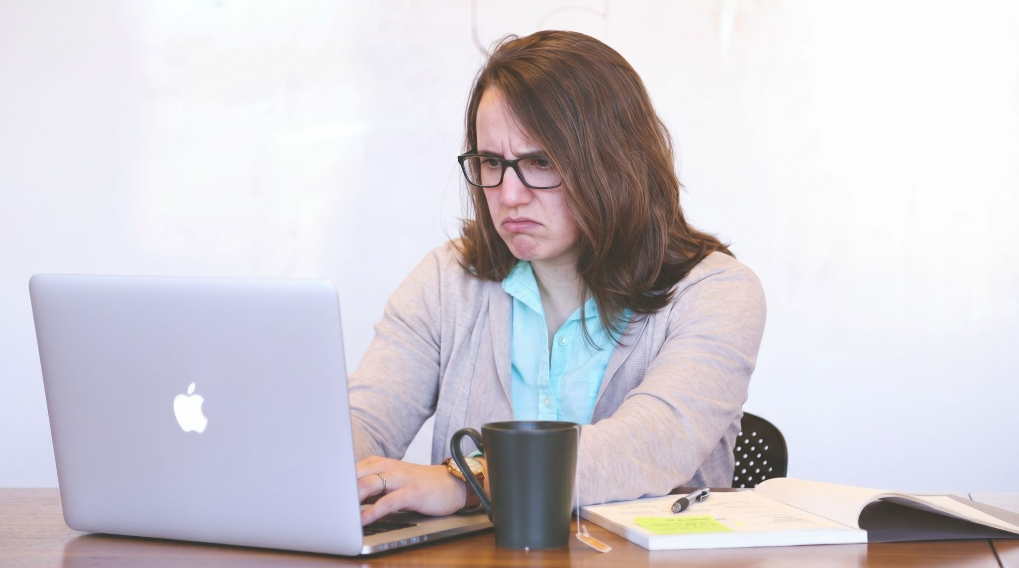 Employee at a desk reviewing a suspicious email on a laptop, with a cautious expression