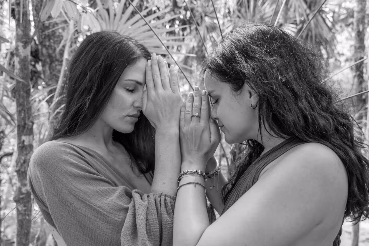 Portrait of two women with namaste hands in the rainforest