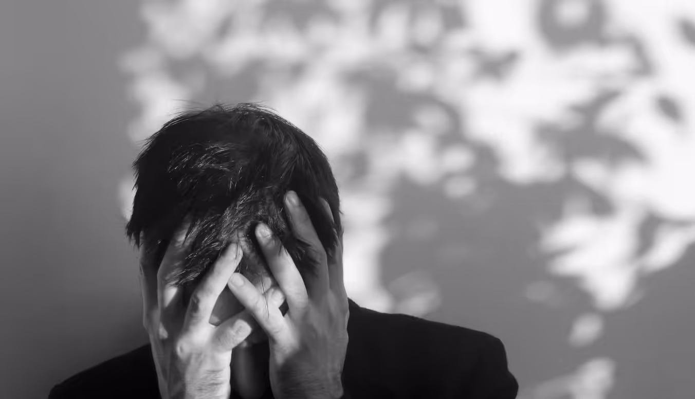 Person leans forward and holds their head in their hands