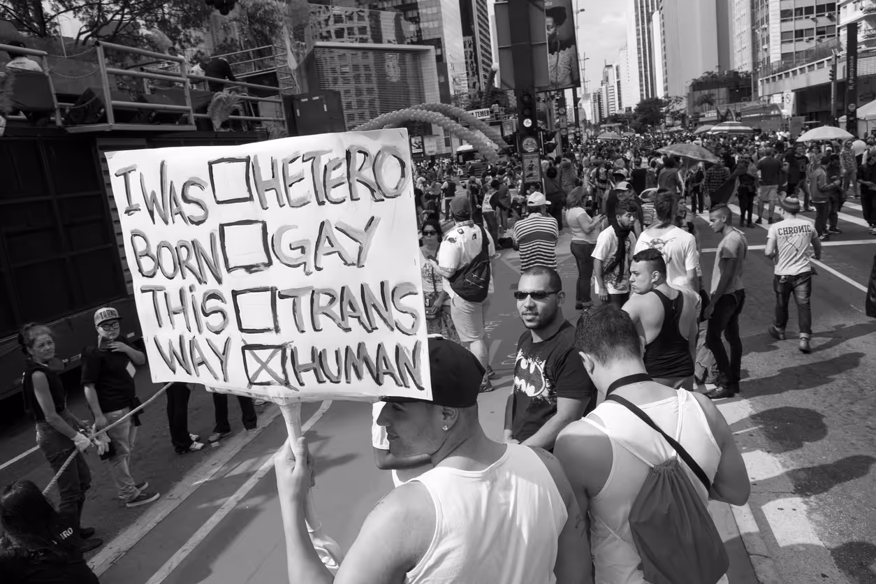 A person holds a sign that reads I was born this way.