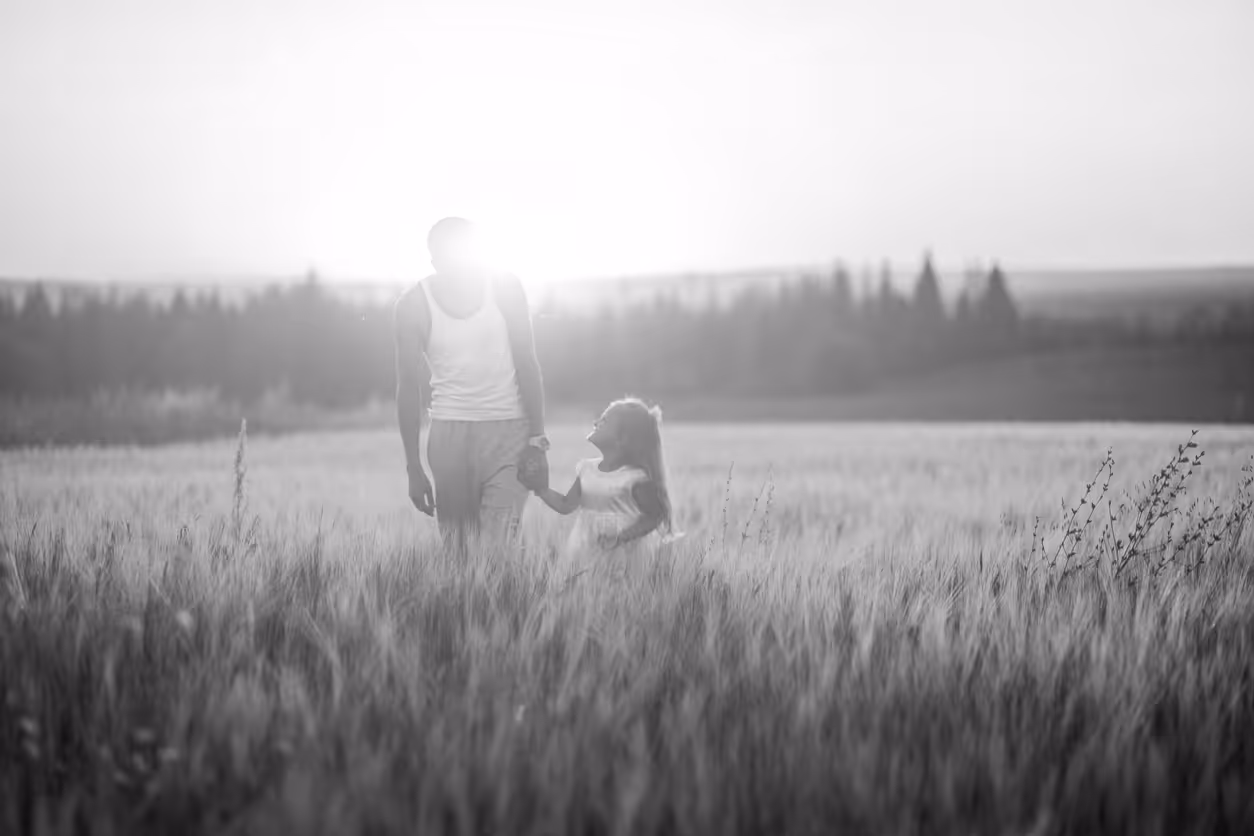 Parent and child walk in a field at sunset