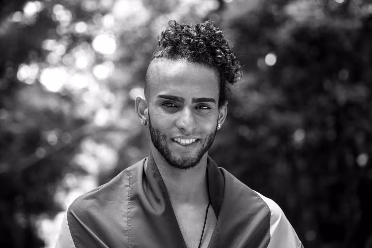 Man smiling at the camera, surrounded by nature