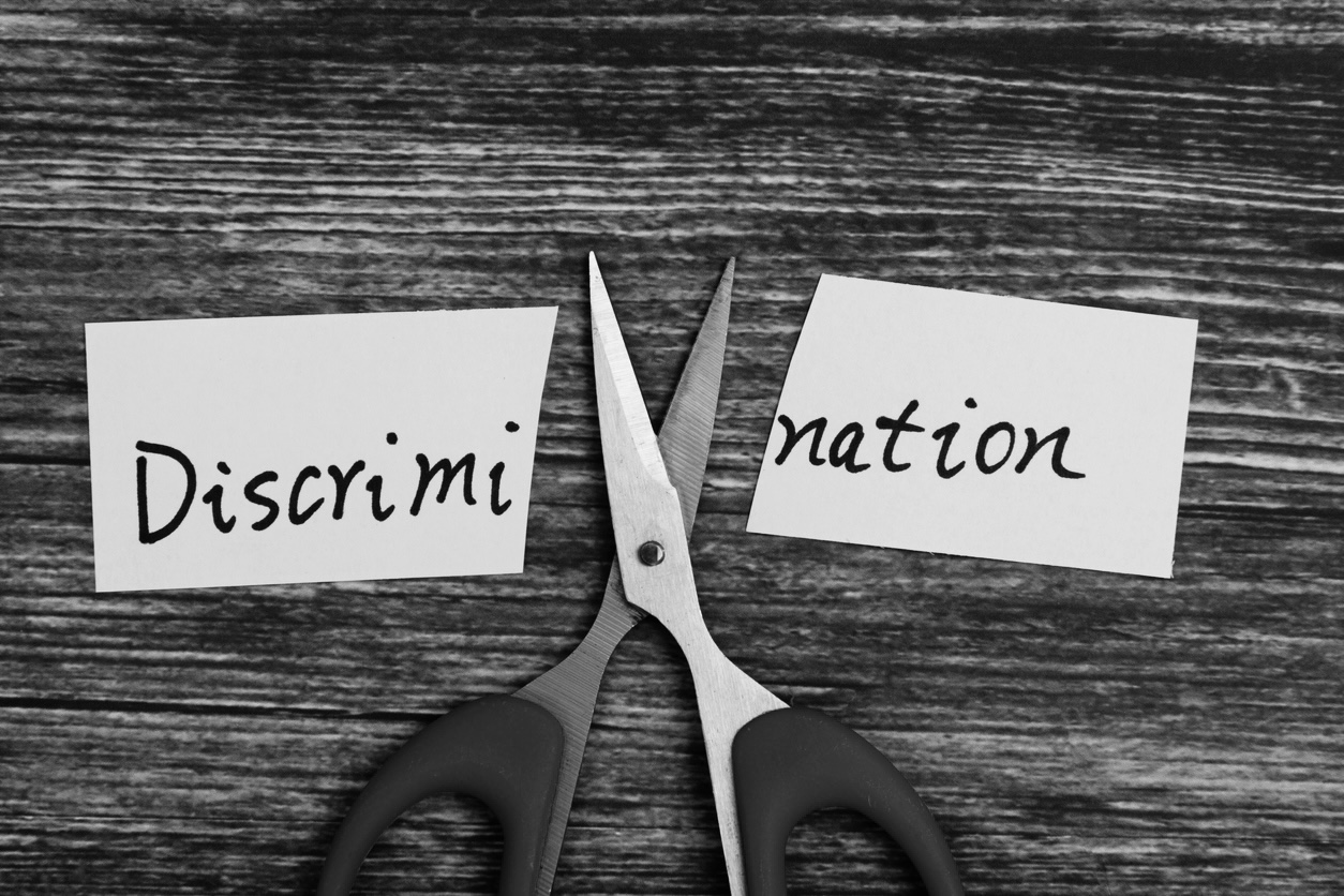 Immigration Pathways for Trans US Citizens Image of Scissors Cutting the Word Discrimination in Half