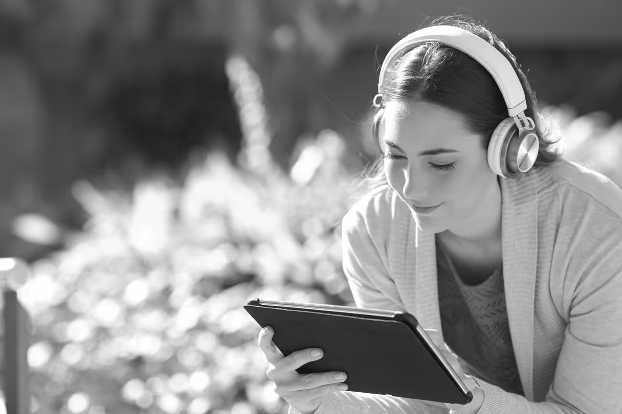 Person with headphones on reading a tablet PC