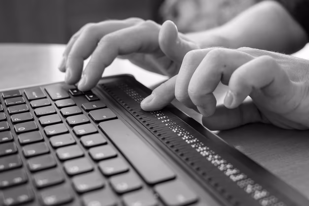 A blind person accesses a Braille display on a computer keyboard