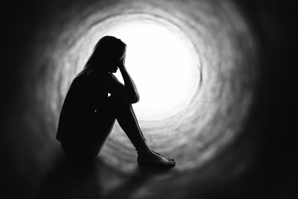A person sitting on the ground with their head in their hands