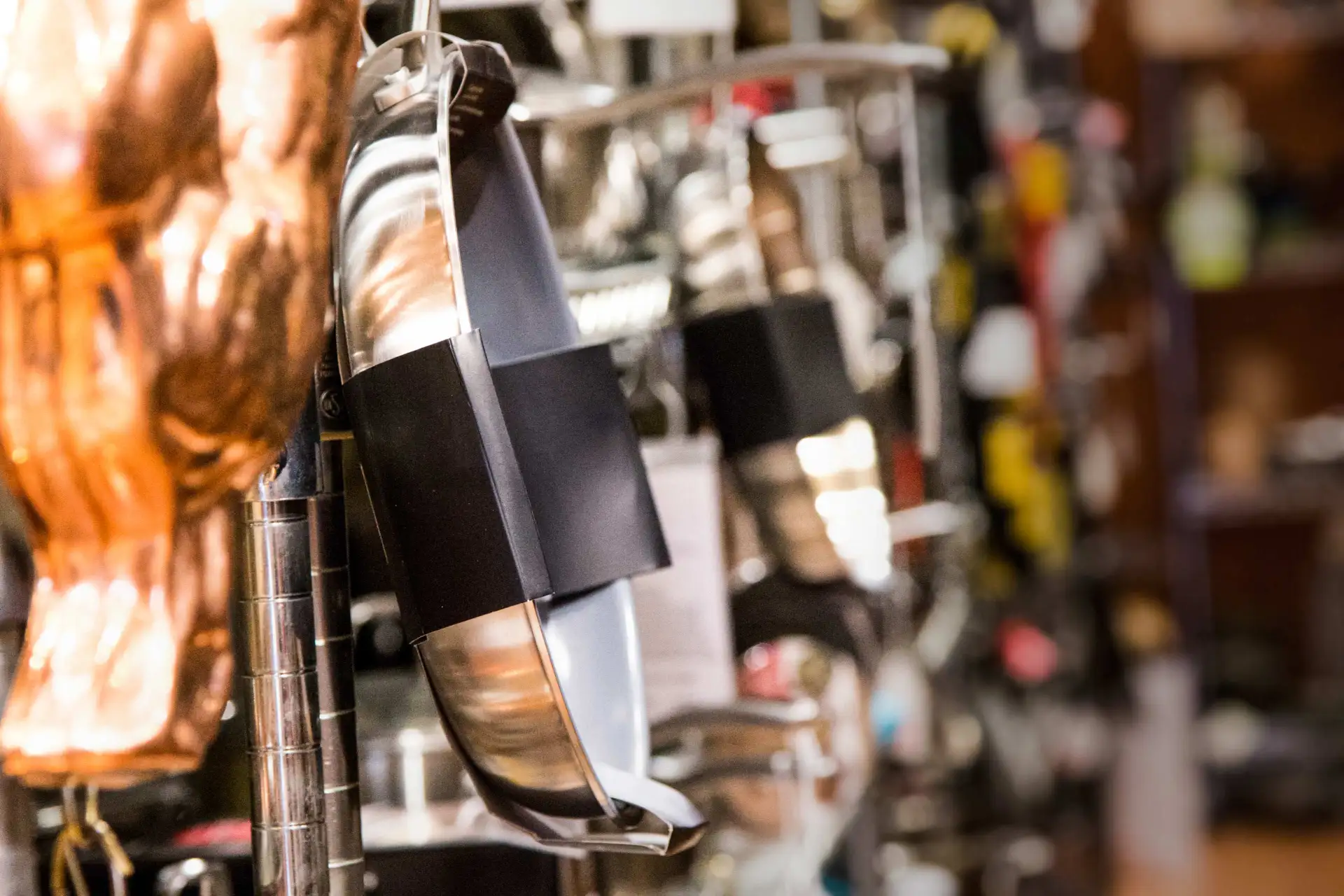 A photograph of pots and pans lining a store shelf inside of Sparrow Hawk Cookware. Website and photography by Paper Krane.