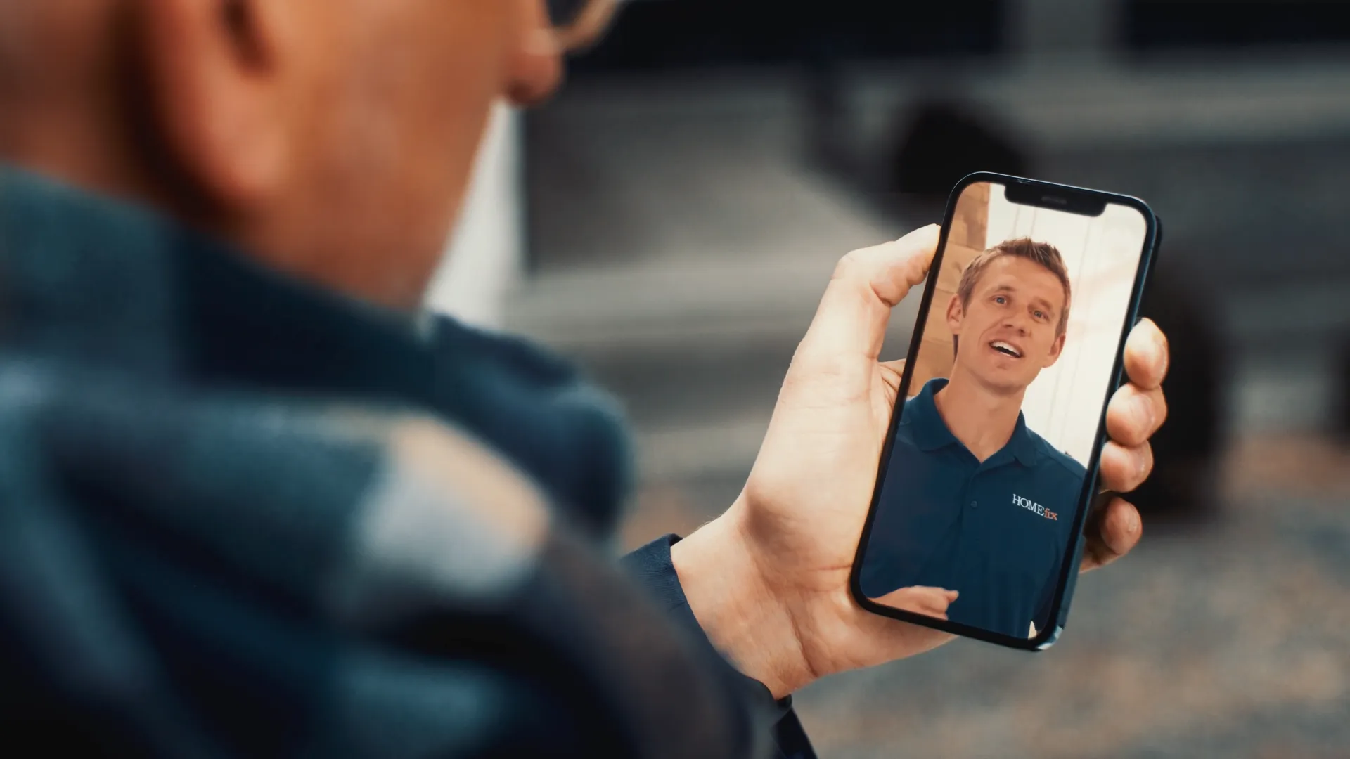 A still frame from the HOMEfix 320 hours in a day project where a man is watching the community outreach video from HOMEfix on his cell phone.