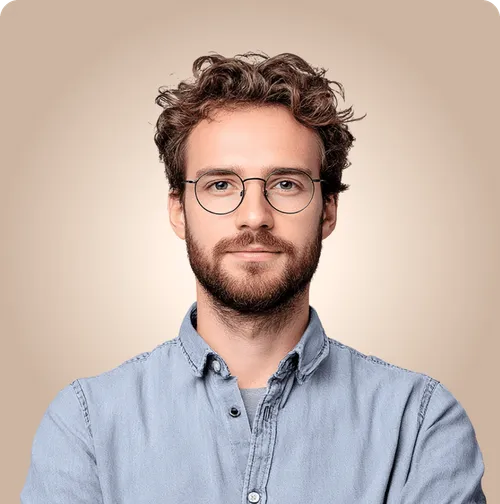 Portrait of man with curly hair and glasses against beige background.