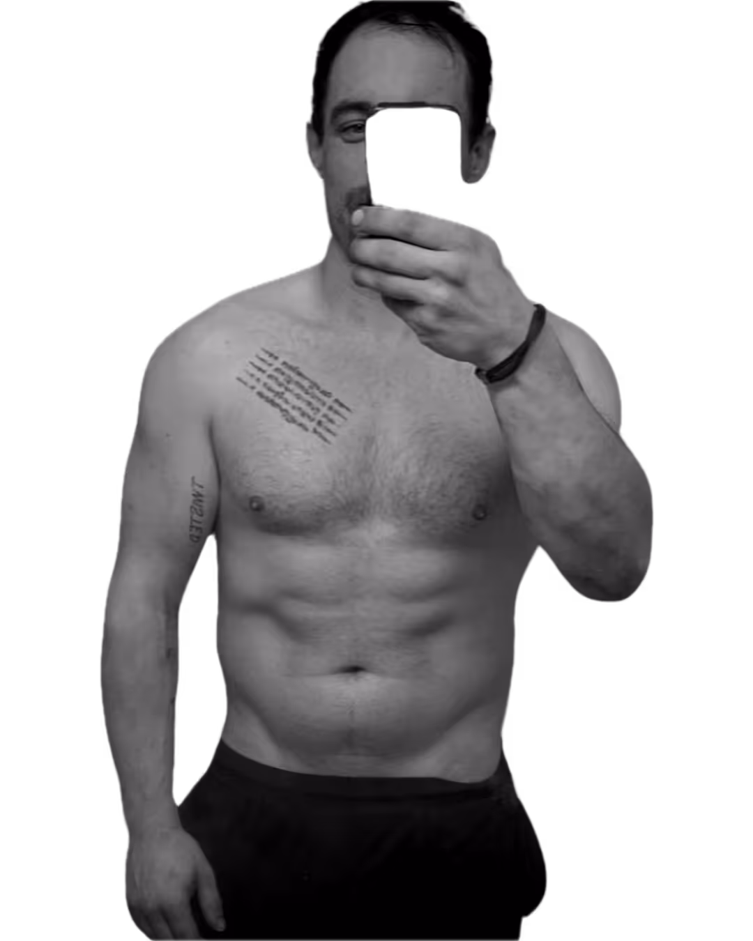 Shirtless man with tattoos on left shoulder and arm taking a selfie with a smartphone in front of his face.