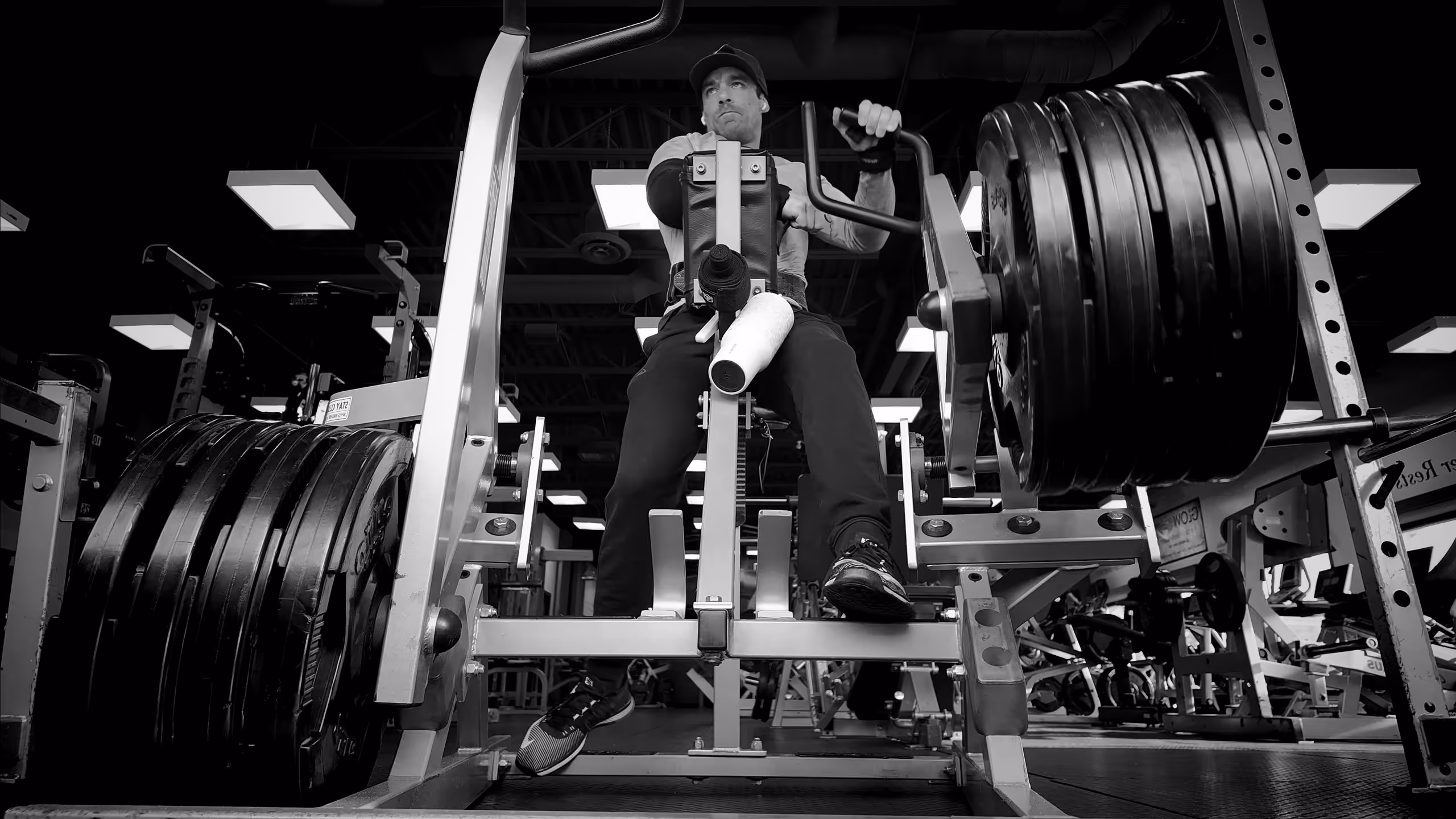 Man lifting heavy weights on gym machine in a fitness center.