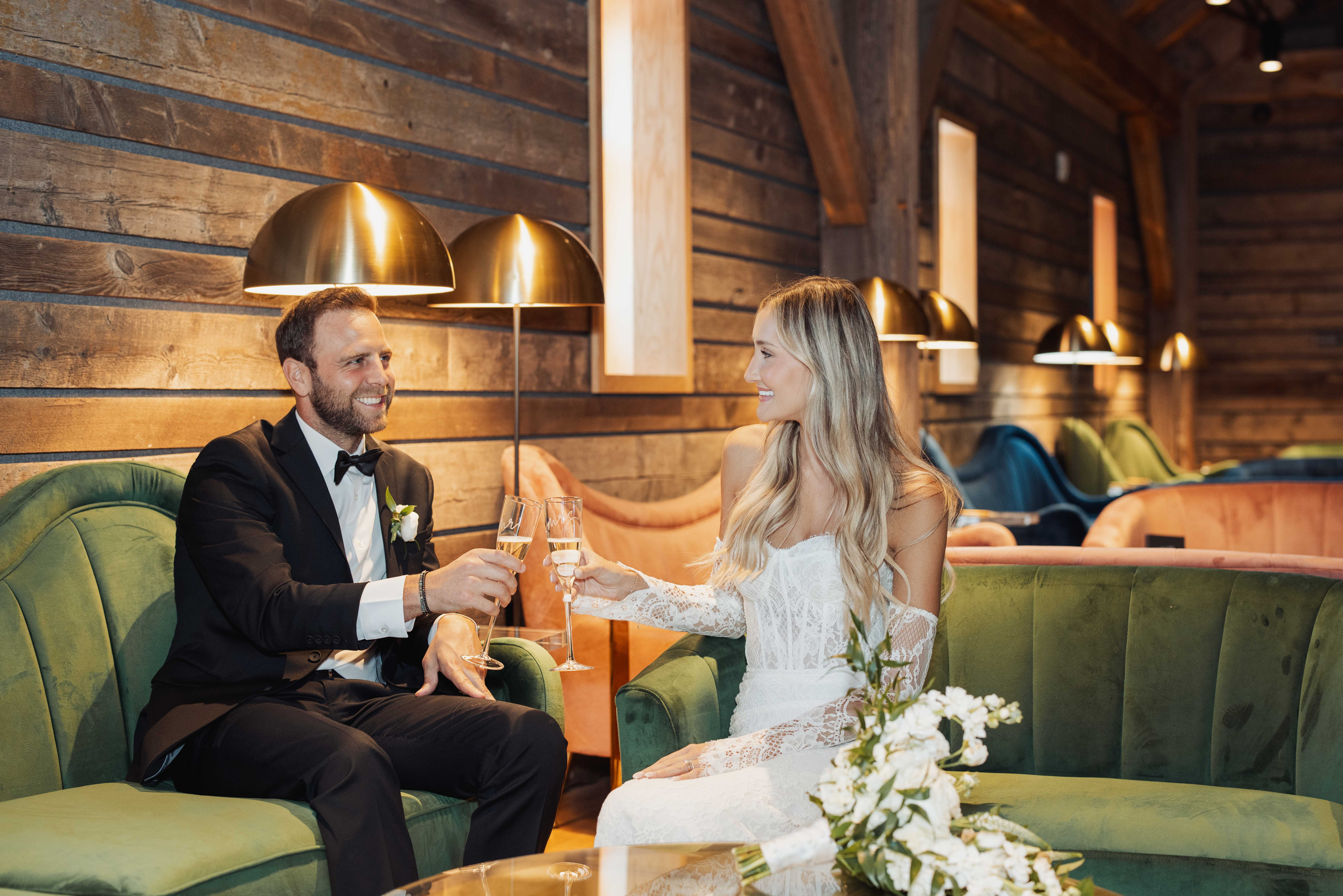A vibrant private event at Harken Hall viewed from the balcony, showcasing guest seating in plush lounge chairs facing a lit stage with the double-H logo background.