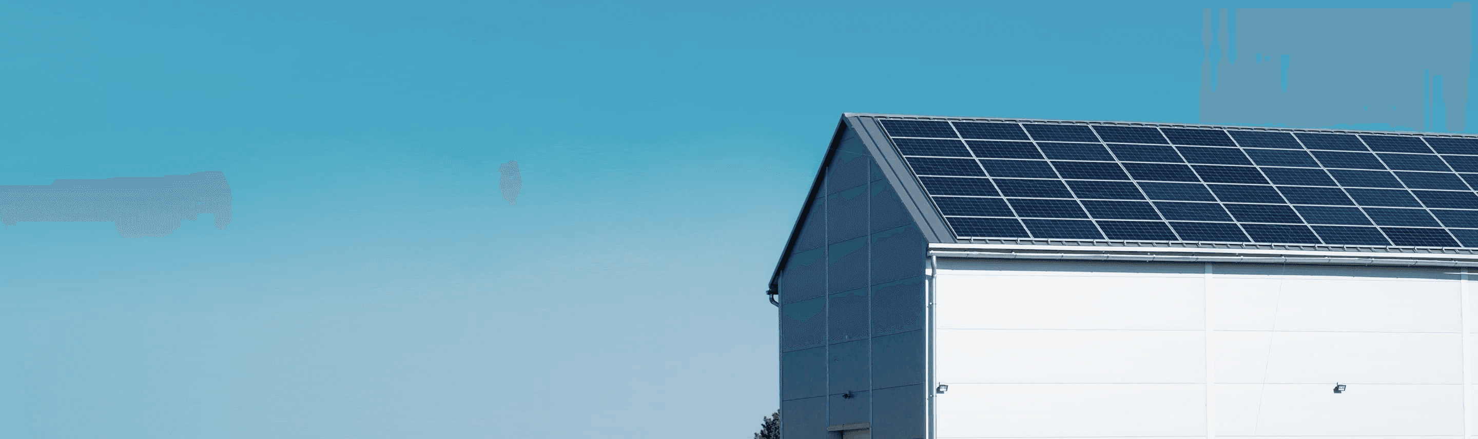 Corner view of a modern building with solar panels installed on its roof against a blue sky.