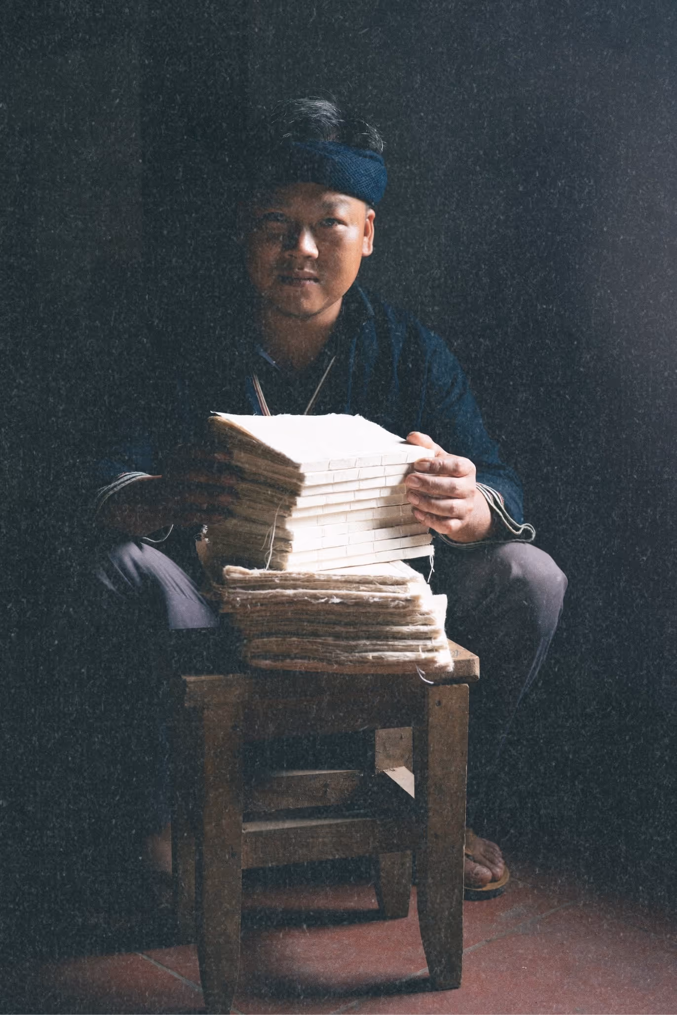 Artisan holding stack of traditional Dao journals in Northern Vietnam representing the Dao ethnic minority heritage.