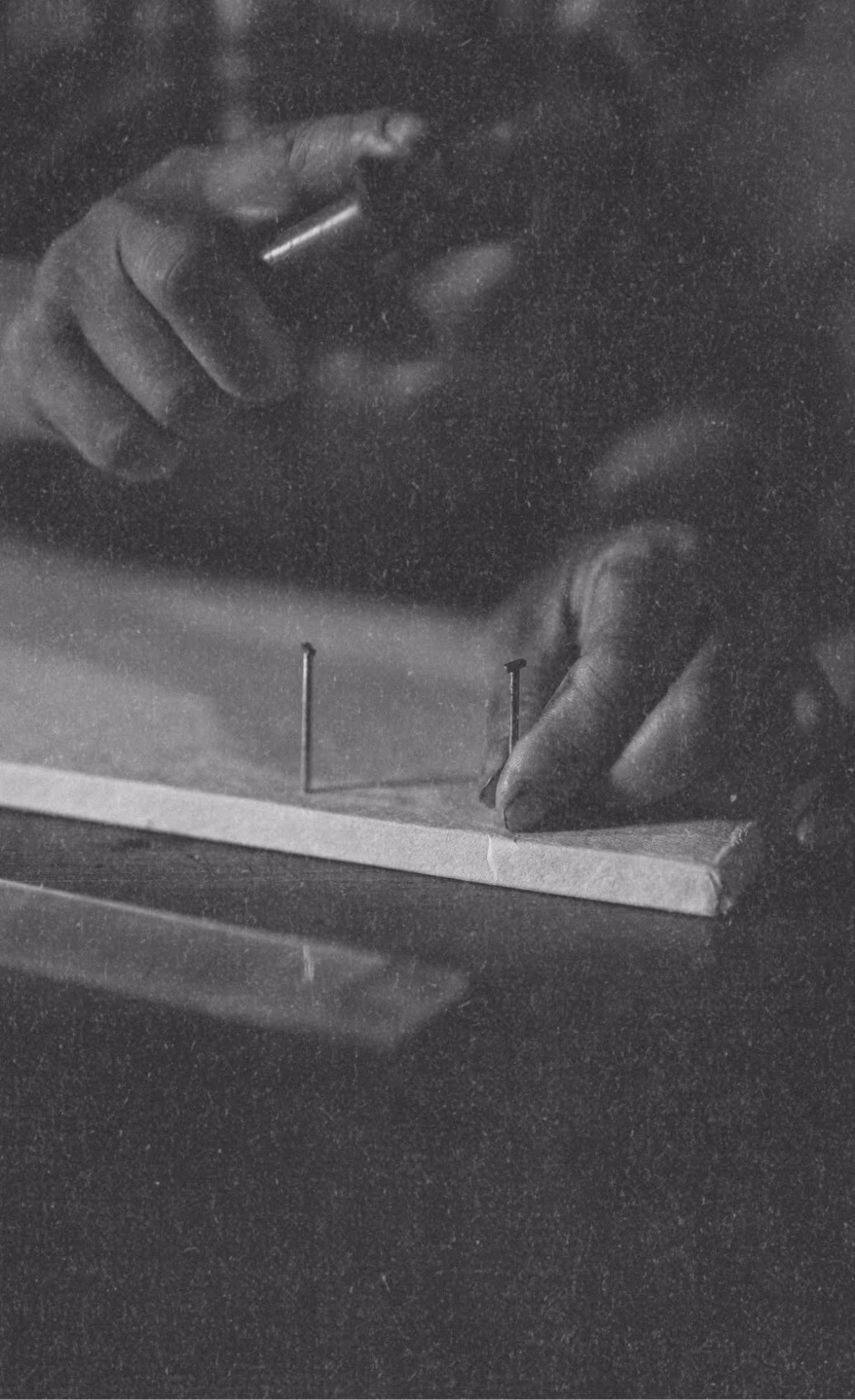 Close-up of hands hammering the holes for binding of a natural fiber journal