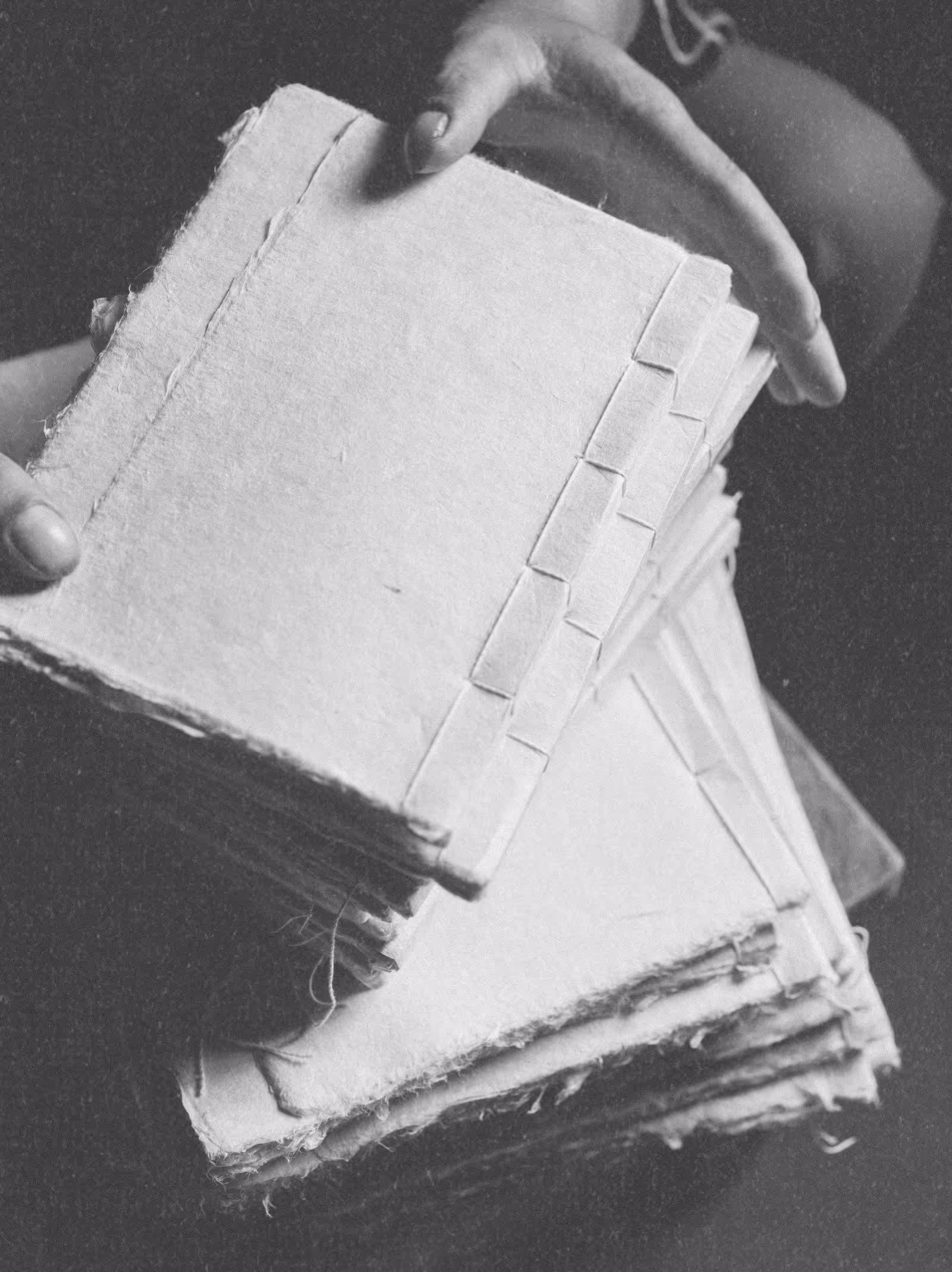 Close-up of hands holding a stack of journals, showing the quality binding of a natural fiber journal