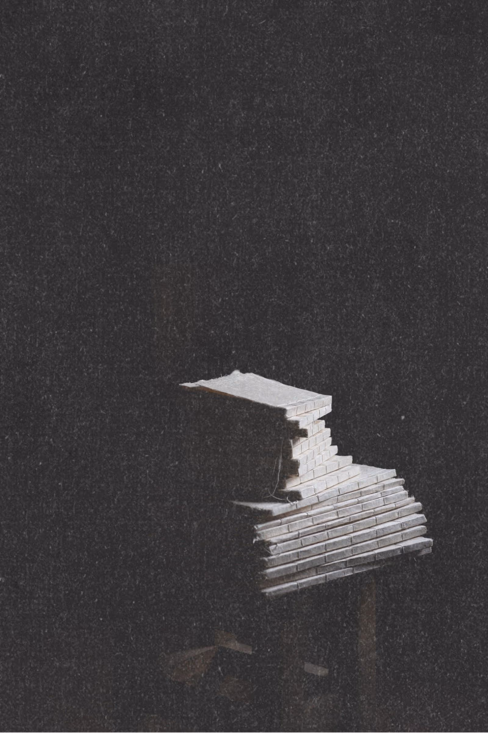 Stack of large handmade journals with varied natural paper textures in mysterious natural setting, evoking a sense of excellence and wonder.