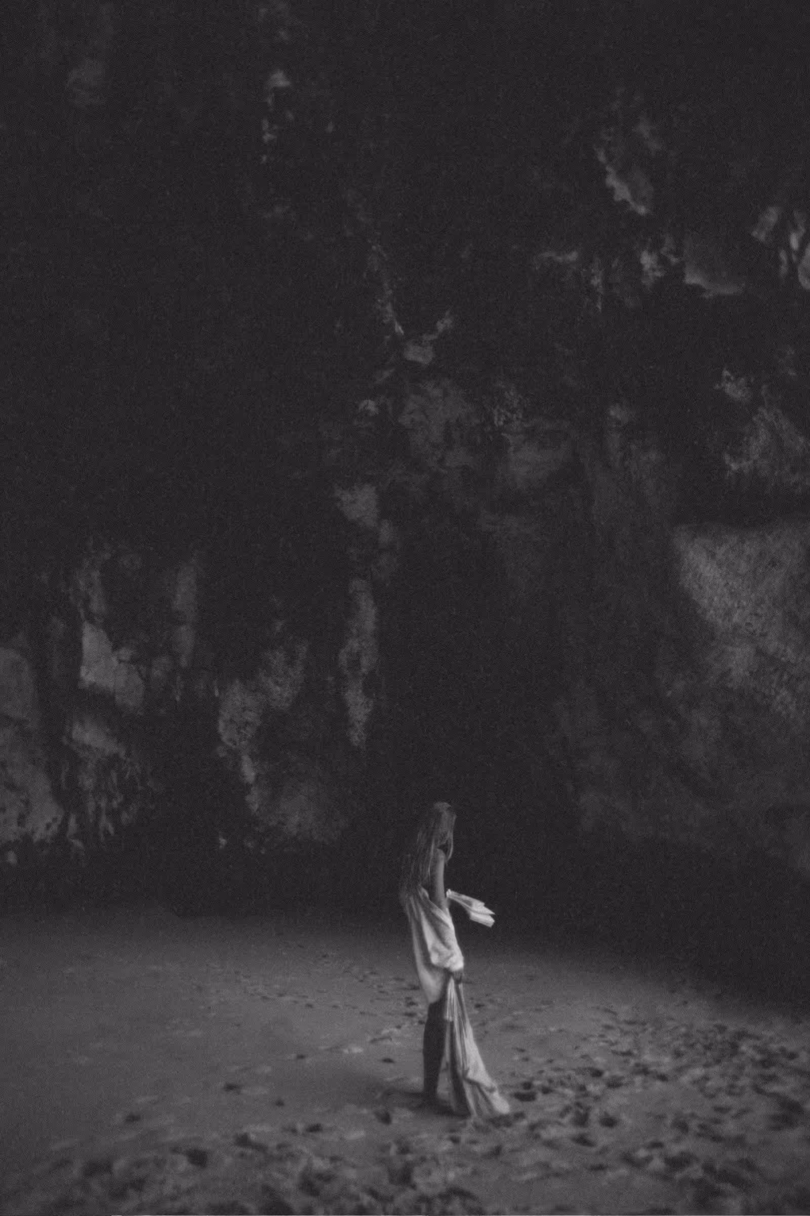 Black-and-white image of woman journaling in serene, contemplative pose with handmade paper notebook