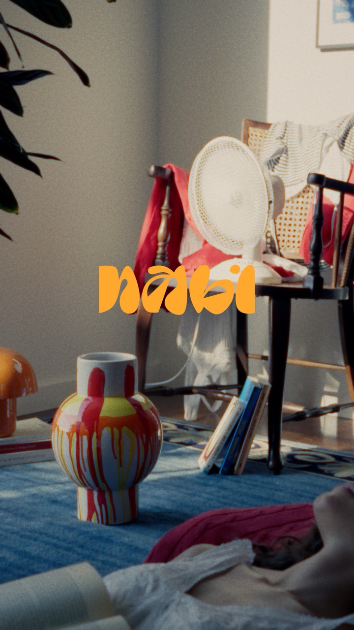 A room with a ceramic jar. In the front is a woman sleeping with a book and in the background is a chair with a ventilator.