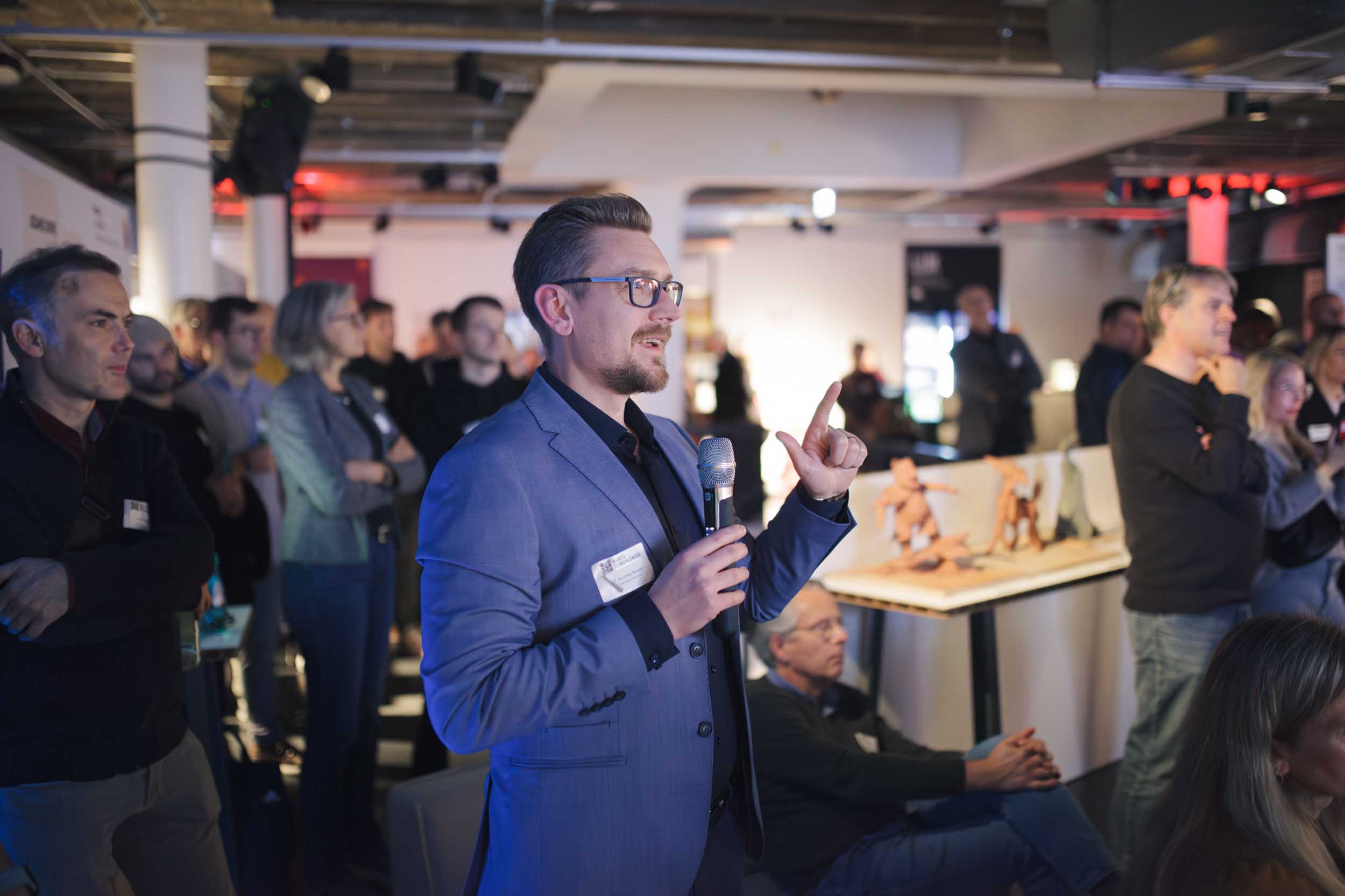 A photo of a man talking into a microphone on an event
