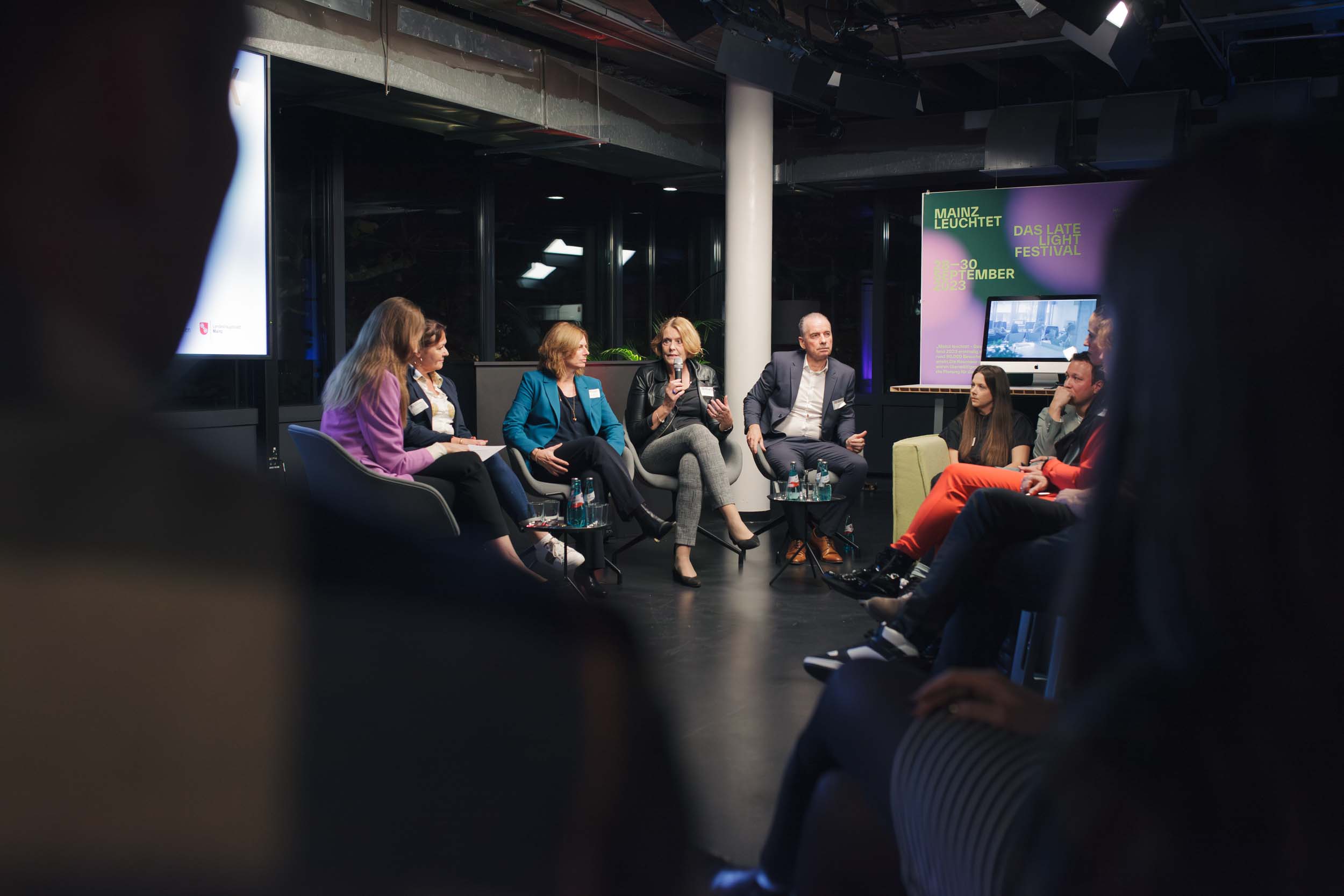 Five people in front of a crowd are discussion