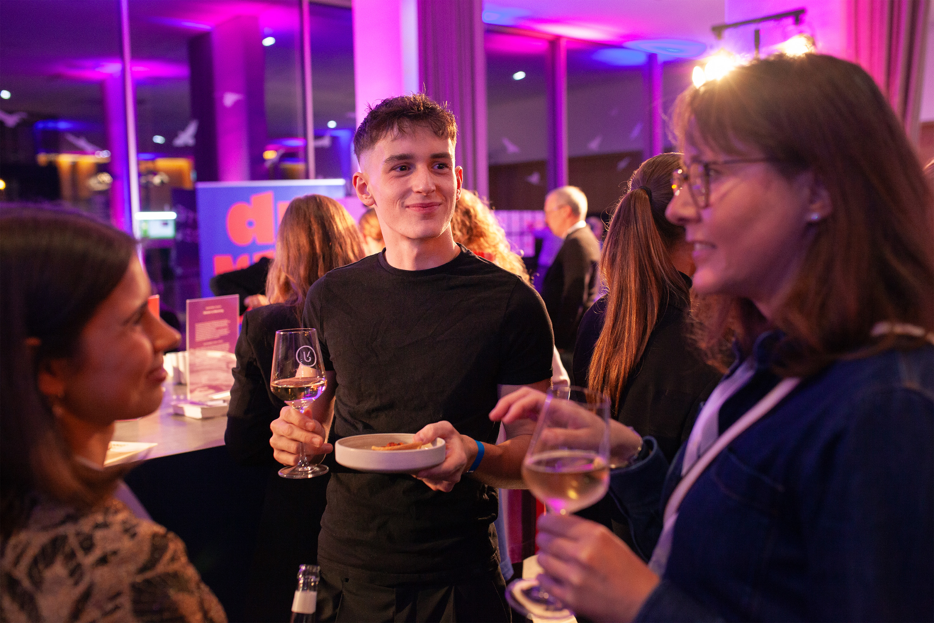 Um jovem com um copo de vinho num evento
