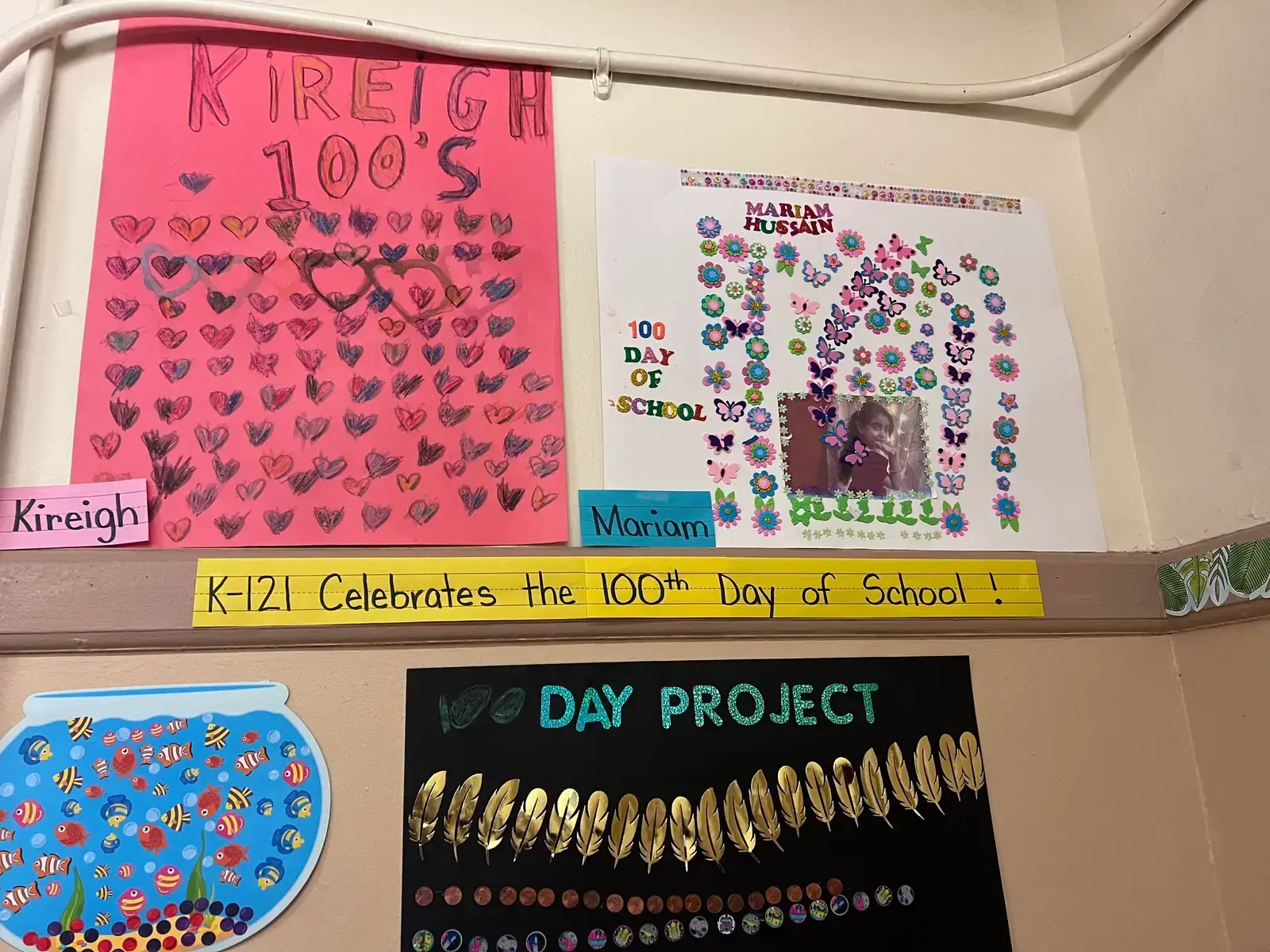 Student projects displayed on bulletin board celebrating 100th day of school