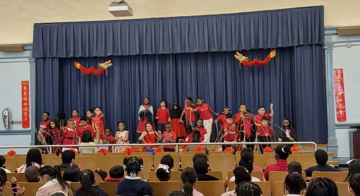 Students performing Lunar New Year show on decorated school auditorium stage