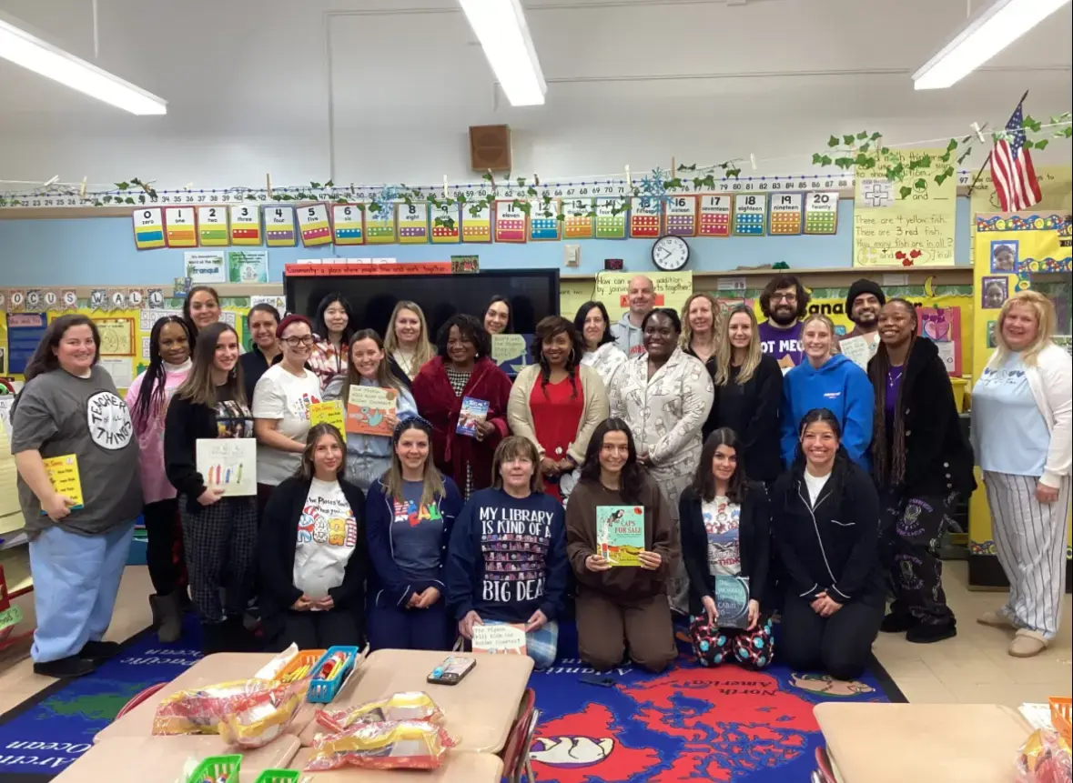 Staff and community members holding books in an elementary classroom