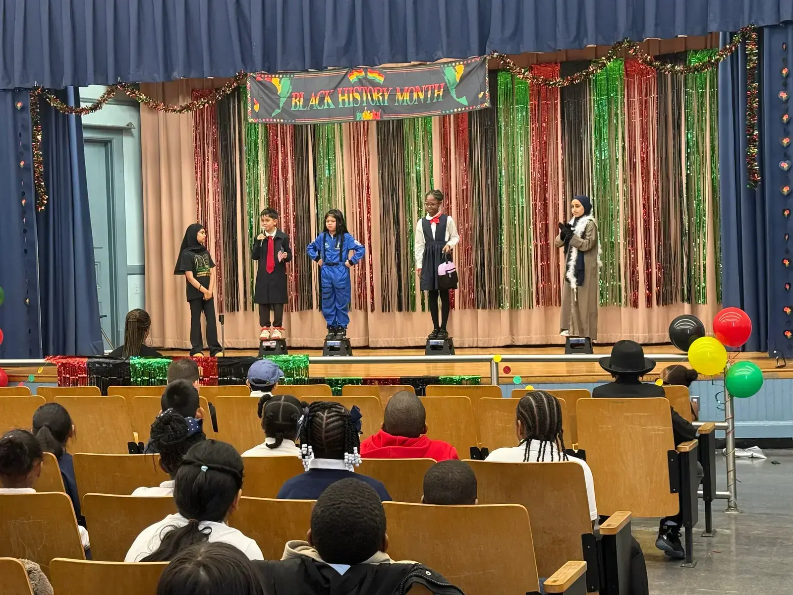 Students in costume perform on stage at Black History Month assembly