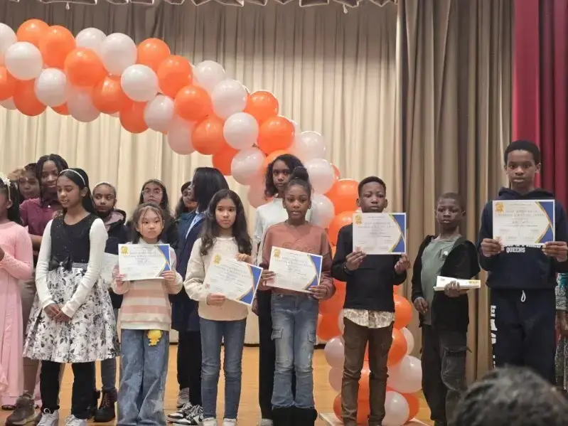 Students holding certificates on stage at a school awards ceremony