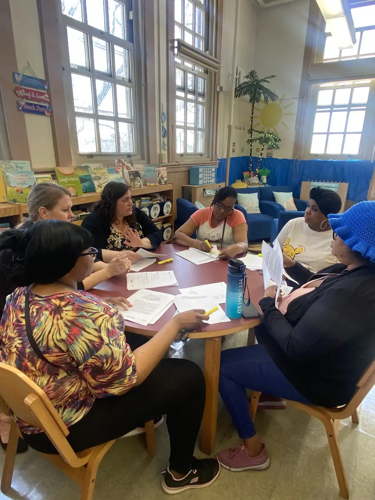 Teachers collaborating around a table reviewing documents in classroom