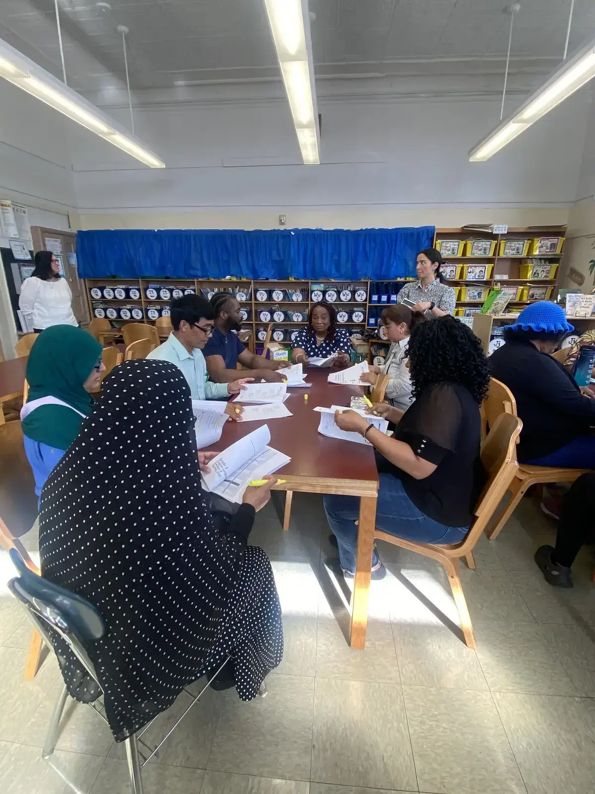 Teachers and staff reviewing documents during a school meeting