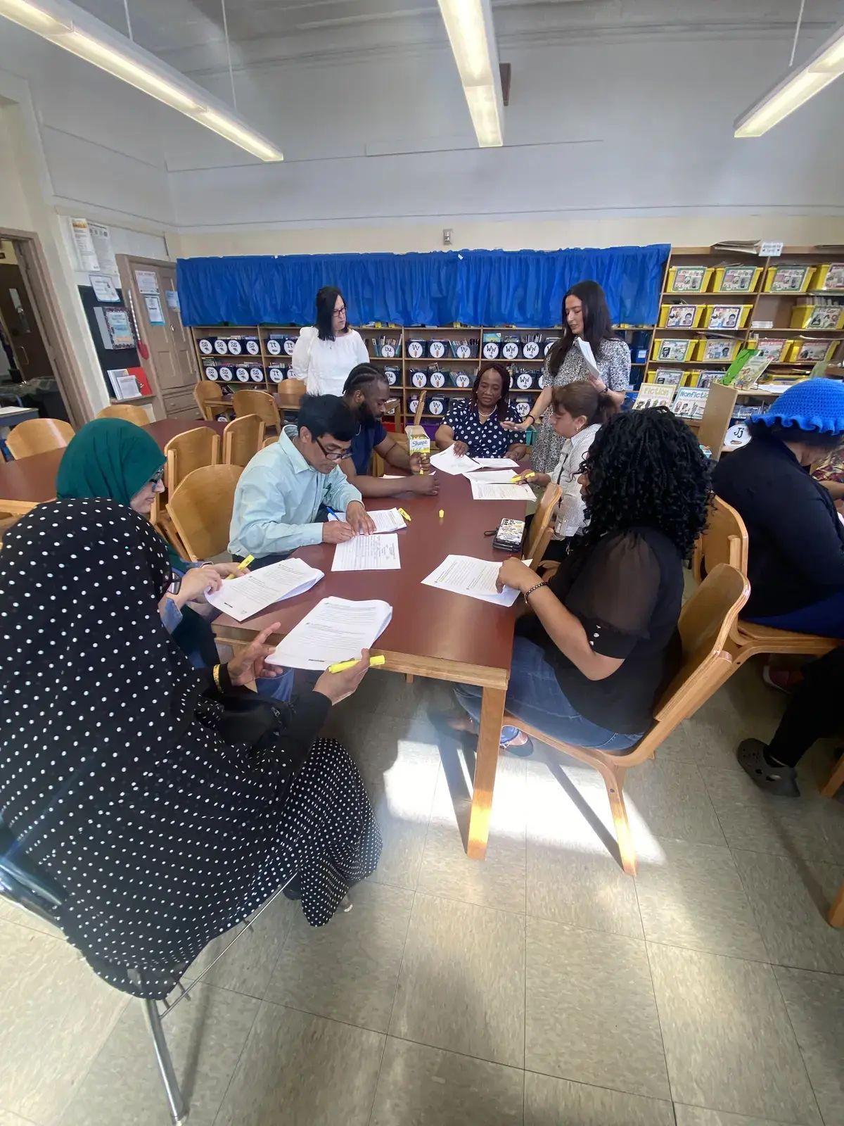 Teachers and staff reviewing documents together in school library