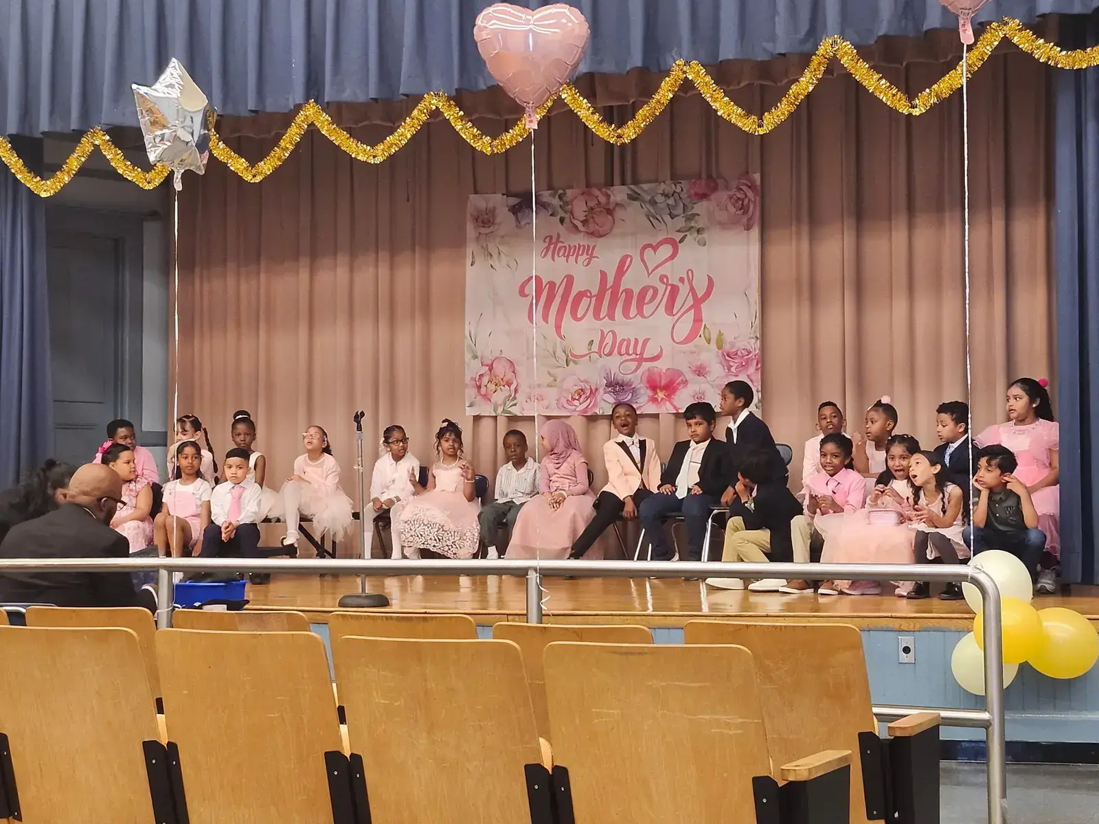 Students performing on stage at a school Mother's Day celebration